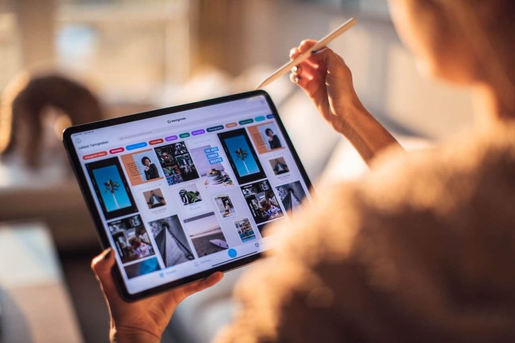 Mulher segurando um tablet e olhando uma galeria de imagens em um site.